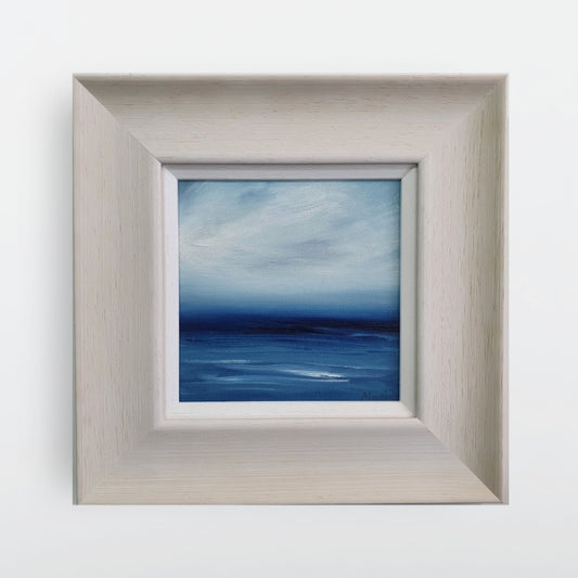 Blue seascape in oil with a broad cream frame.