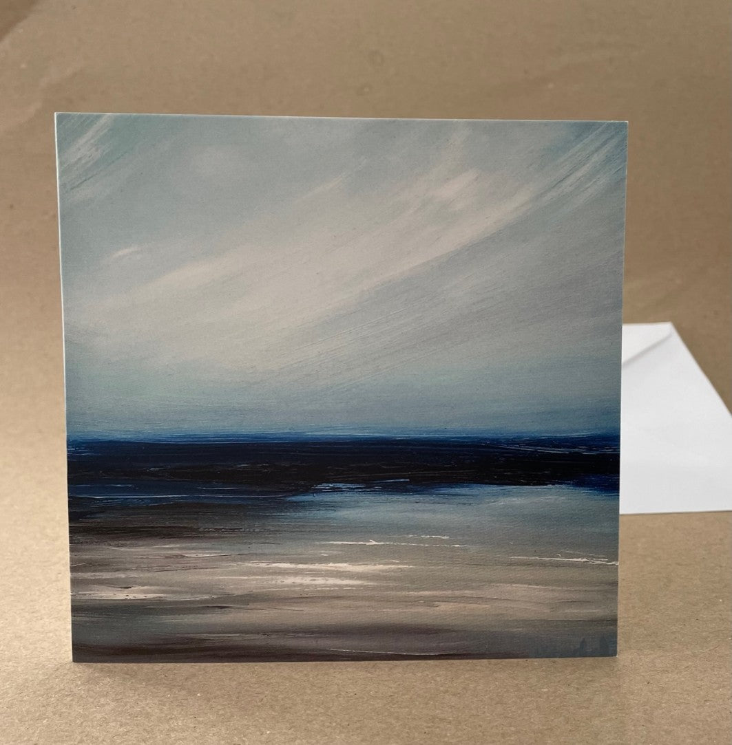 Square greetings cards laid flat with a white envelope atop brown background.