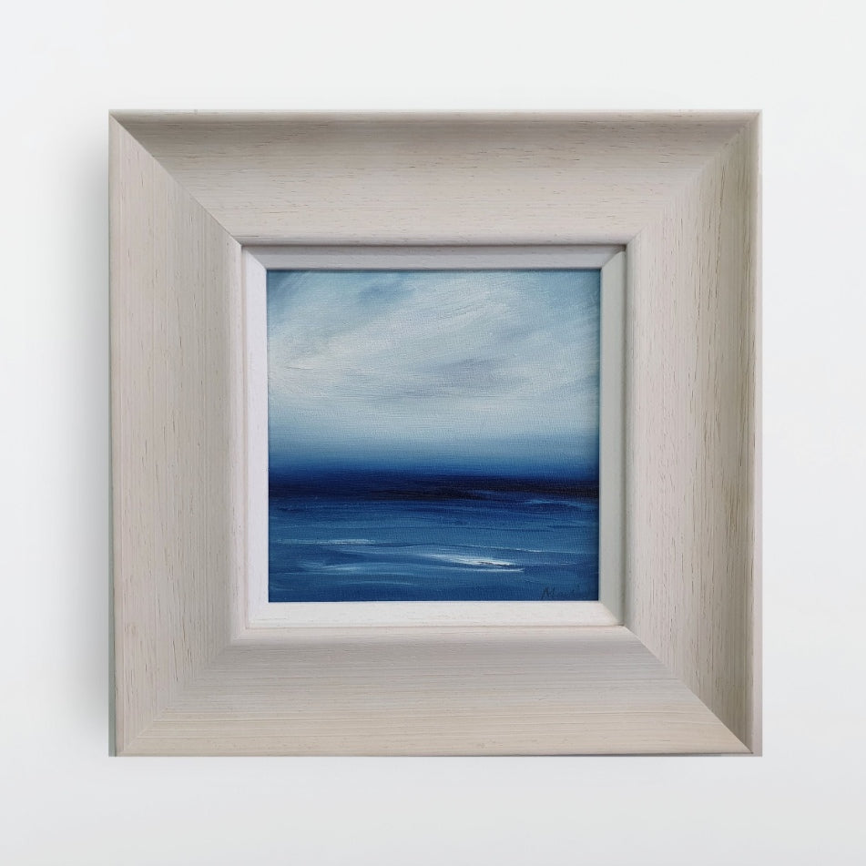 Blue seascape in oil with a broad cream frame.