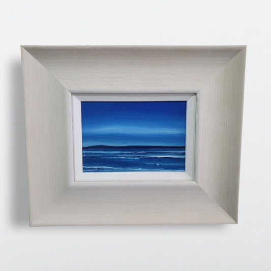 Blue Hebridean seascape oil painting set in a broad off-white frame.