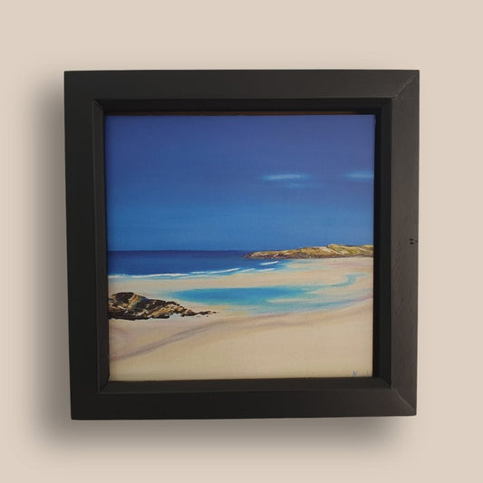 Black framed image of a sandy beach and blue sea and sky.